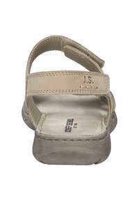 Beżowe skórzane sandały z dwiema regulowanymi paskami, miękką wkładką i gumową podeszwą. Posiadają wytłoczone inicjały "J.S." blisko paska.