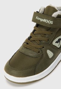 Olivovo zelené vysoké tenisky KangaROOS s polstrovaným golierom, suchým zipsom, logom kengury, zvrškom z textilu a kože a bielou podrážkou.