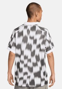 Korte mouw, gekleed shirt van lichtgewicht stof met een zwart-wit abstract patroon, raglanmouwen en een effen witte kraag.