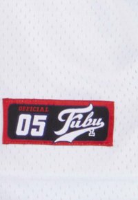 Balts acu stīgs audums ar melnu etiķeti, kas rotāta ar sarkaniem akcentiem un baltu tekstu "OFFICIAL 05 Fubu." Teksturēta virsma ar maziem caurumiem.