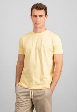 Helles gelbes T-Shirt mit Rundhalsausschnitt aus strukturiertem Stoff, das ein kleines blaues Logo auf der Brust und kurze Ärmel hat. Lässige Passform.
