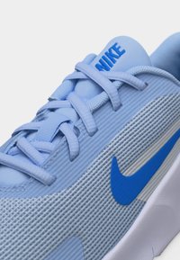 Ανοιχτό μπλε αθλητικό παπούτσι Nike με μπλε λογότυπο swoosh, ανοιχτό μπλε κορδόνια και την επιγραφή «NIKE» στη γλώσσα.