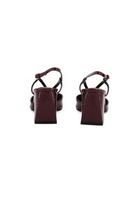 Sandali con tacco a blocco in pelle patinata borgogna, dotati di cinturini regolabili alla caviglia e una finitura liscia, che presentano un design moderno e minimalista.