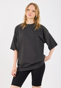 T-shirt nera in cotone oversize con maniche corte, scollatura rotonda e vestibilità morbida, abbinata a pantaloni bici neri a coste. Design semplice.