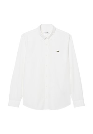 Camisa blanca de manga larga en algodón, con cuello abotonado, cierre frontal con botones y un pequeño logo verde de Lacoste en el pecho izquierdo.