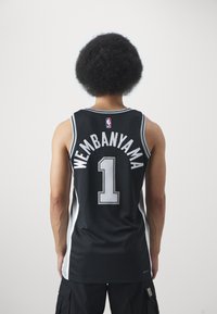 Juodas krepšinio marškinėliai su baltais akcentais, ant nugaros yra užrašas "WEMBANYAMA" ir numeris "1". Pagaminti iš kvėpuojančios tinklinės medžiagos.