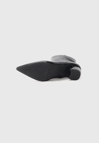 Stivaletto in pelle nera con punta appuntita e tacco spesso, caratterizzato da una superficie liscia con sottili scanalature orizzontali sulla suola.