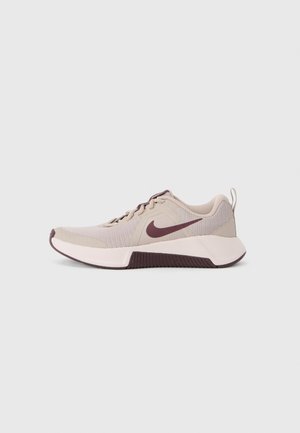 Beige athletic shoe with a mesh upper, maroon accents, and a textured dark sole. Features a rounded toe and fabric laces.