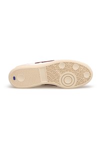 Biała podeszwa sneakersów z teksturowanym wzorem, beżowa gumowa podeszwa, okrągłe akcenty oraz kontrastujący ciemny element na krawędzi bocznej.