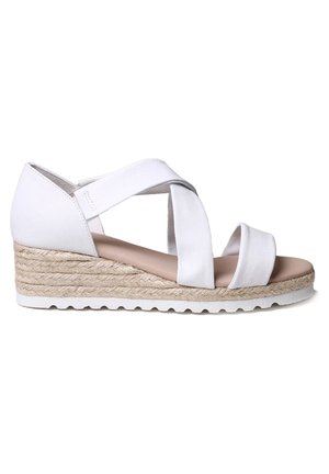 Sandale compensée blanche avec lanières croisées, semelle plateforme enveloppée de jute et semelle intérieure rembourrée couleur tan, sur un fond blanc uni.