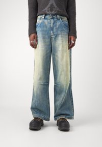 Jeans a gamba larga di un azzurro chiaro con un effetto sbiadito e strappato. Il tessuto in denim presenta tasche frontali e una vita con bottone.