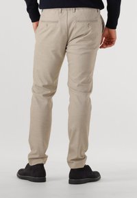 Beige trousers with a smooth texture, two back pockets with buttons, and black suede shoes. Tailored fit, straight leg design.