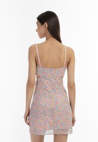Rochie cu model floral, cu bretele roz, dintr-un material ușor, cu un corset ajustat și o fustă ușor evazată, având un design cu spatele deschis.
