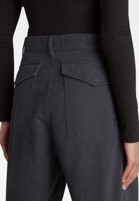 Mörkgrå denimbyxor med hög midja och en åtsittande design, som har två rymliga bakfickor och subtila vertikala ribbor.