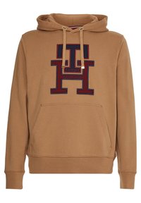 Světlě hnědá mikina s kapucí a přední klokankou. Obsahuje vyšívané logo "TOMMY HILFIGER" v námořnické a červené barvě. Materiál z cotton blend.