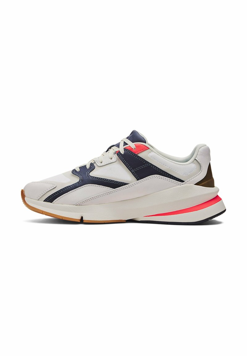 Zapatilla deportiva con parte superior blanca y navy, paneles texturizados y acentos rojos. Cuenta con una suela acolchada y una suela de goma para tracción.