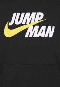 Tela negra con texto blanco "JUMP MAN" y un gran logotipo de swoosh de Nike en amarillo que se superpone parcialmente al texto.