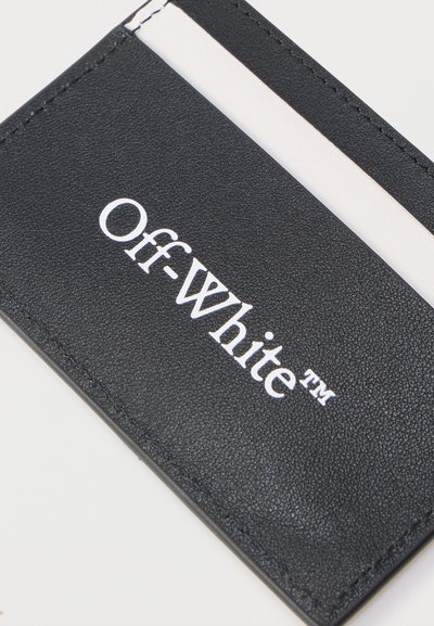 Črno-beli držalo za kartice Off-White z vidnim belim logotipom in šivanimi robovi na svetli površini.