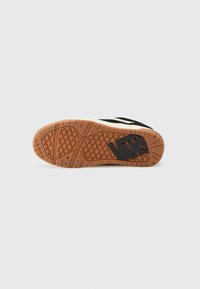 Vans shoes featuring a black upper with white accents, a textured gum rubber sole, and a prominent logo on the bottom.