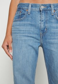 Blå denimjeans med en smal passform, utrustade med fem fickor, mässingsdetaljer och kontrasterande sömmar. Slät textur och blekt tvätt.
