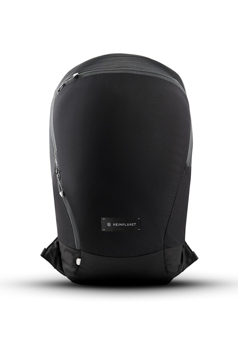 Mochila negra con una textura suave y mate. Presenta cremalleras en los lados, una parte superior de malla texturizada y un parche con el logo en la parte inferior.