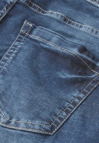 Tissu en denim, couleur bleu foncé, avec une poche arrière présentant des détails de couture visibles en marron clair. Texture lisse, coupe classique.