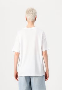 White short-sleeve t-shirt made from cotton, featuring a relaxed fit, round neckline, and visible stitching details on the hem.