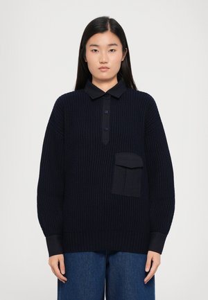 Navy ribbed knit pullover with a pointed collar, three buttons, and a large pocket on the left chest. Features wide sleeves and cuffs.