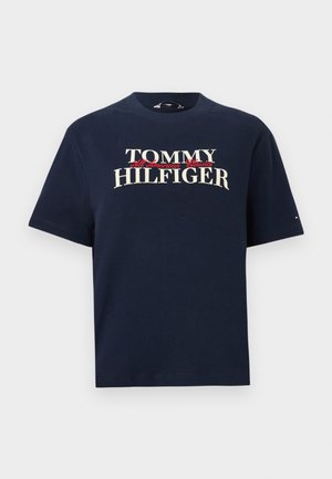 Tummansininen puuvillainen t-paita, jossa teksti "TOMMY HILFIGER" punaisella korostuksella, pyöreä kaula-aukko, lyhyet hihat ja rento istuvuus.