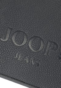 Portafoglio nero testurizzato con logo in rilievo "JOOP! JEANS", con finitura liscia e motivo sottile per una presa migliore.