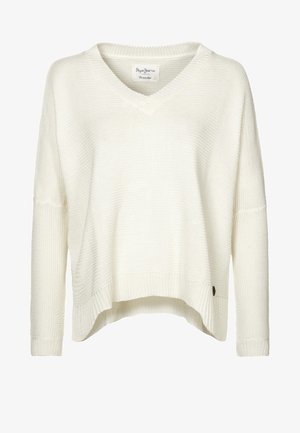 Kremowy sweter z dzianiny z dekoltem w serek, luźnym fasonem, opadającymi ramionami i ściągaczem u dołu. Posiada małą metkę marki po bokach.