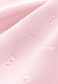 Vaaleanpunaista kangasta, jossa on sileä pinta ja kohokuvioidut kirjaimet "B" ja "BAKER." Hienovarainen poimutus lisää syvyyttä designiin.