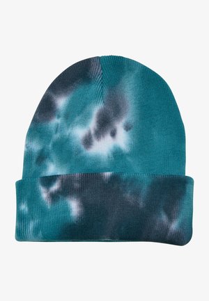 Pletena kapa v teal barvi z vzorcem tie-dye, ki vsebuje temno modre in sivo odtenke. Mehak material in zasnova s prepogibom.