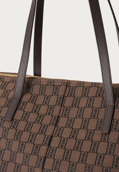 Sac cabas marron à motifs avec des lanières en cuir marron foncé et une fermeture éclair dorée visible sur le bord supérieur.