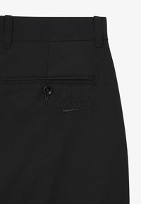 Pantalones negros de tela texturizada con un diseño elegante. Cuentan con un bolsillo trasero asegurado con un botón y un logo bordado.