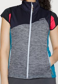 Grå, texturerad väst med hög krage, framdragkedja och sidofickor. Har svarta och rosa detaljer på axlarna och teal-färgade sidor.