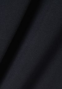 Close-up van donker marineblauwe stof met fijne gebreide textuur en zachte plooien.