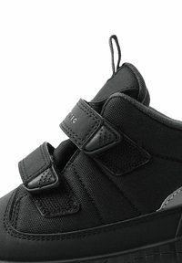 Schwarzer sportschuh mit einem strukturierten Stoffobermaterial, zwei Klettverschlüssen und einer verstärkten Gummisohle sowie einer Zuglasche an der Ferse.