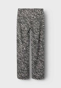 Pantalons à rayures zèbre noir et blanc avec une coupe droite, dotés d'une taille élastique et de deux poches arrière. Fabriqués à partir d'un matériau doux et texturé.