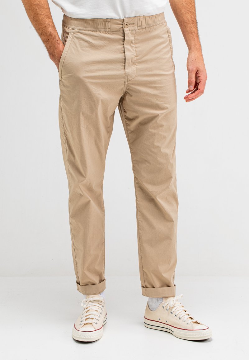Beige, lichtgewicht chino broek met een elastische tailleband, knoopsluiting en rechte pijpen; heeft zijzakken en opgerolde manchetten.