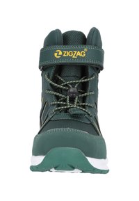 Grüner High-Top-Schuh mit gelbem Logo, strukturiertem Obermaterial, verstärkter Zehenpartie, verstellbarem Riemen und gemusterten Schnürsenkeln. Weiße Sohle für Traktion.