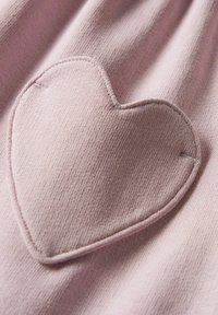Tissu rose présentant une appliqué en forme de cœur avec un fil assorti, affichant une texture douce et une finition lisse.