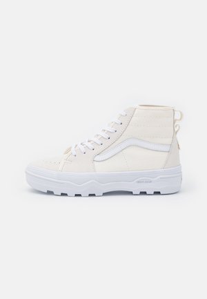 Witte hoge sneaker met vetersluiting, gestructureerde zool en zijstreep detail op een effen achtergrond.