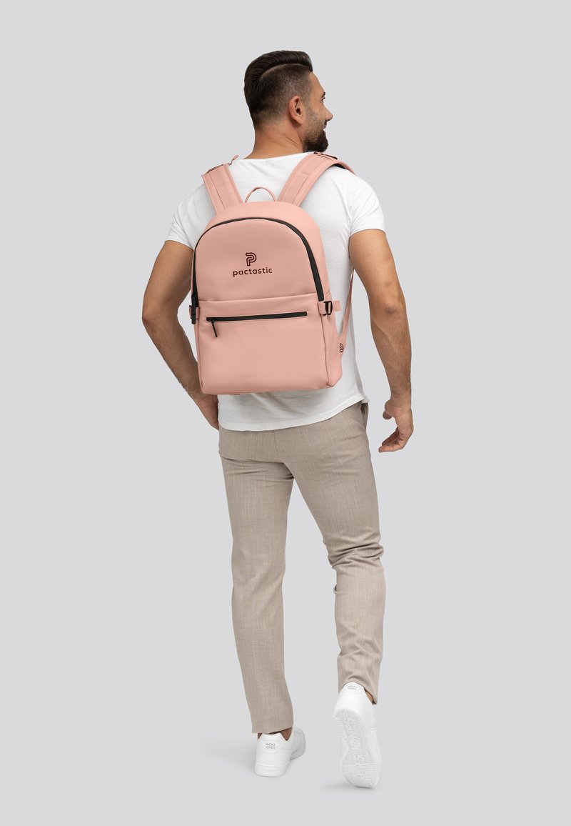 Roze rugzak met een gladde textuur, zwarte accenten en een voorvak met rits. Verstelbare schouderbanden en een logo op het bovenste gedeelte.