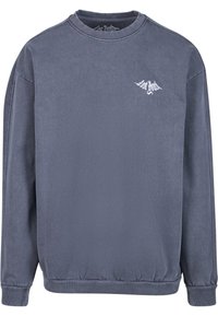 Szürke pulóver, puha anyagból készült, kerek nyakú, hosszú ujjú, kis fehér logóval a mellkasán. Simma textúra.