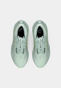 Sneakers da corsa verde chiaro con una tomaia in tessuto testurizzato, chiusura con lacci e una suola liscia con un logo discreto sulla linguetta e sulla soletta.