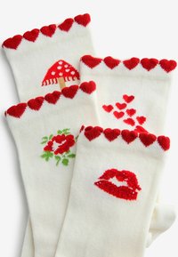 Hvide sokker med røde manchetter med hjerteprint, med motiver af en svamp, roser, spredte hjerter og kysse-læber i kontrastfarver.