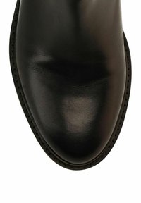 Stivale alla caviglia in pelle nera con texture liscia, punta tondeggiante e cuciture a contrasto lungo la suola. Focalizzazione su un design minimalista.