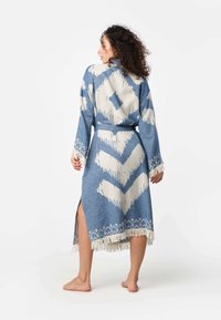 Modrý a biely vzorovaný kimono s dlhými rukávmi, opaskom v páse a frnčovým lemom. Obsahuje chevronové a diamantové motívy. Mäkčený textilný povrch.