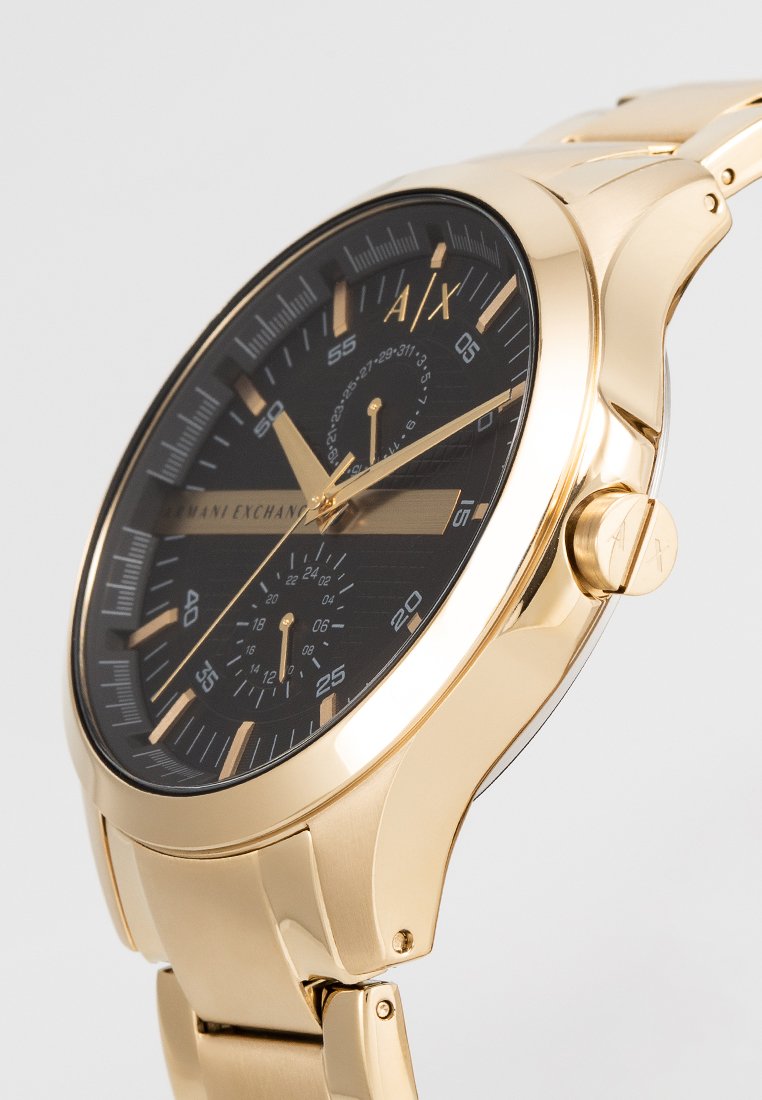 Reloj de acero inoxidable con tono dorado que presenta una esfera negra, tres subesferas, manecillas doradas y un logo grabado. Acabado suave y brillante.
